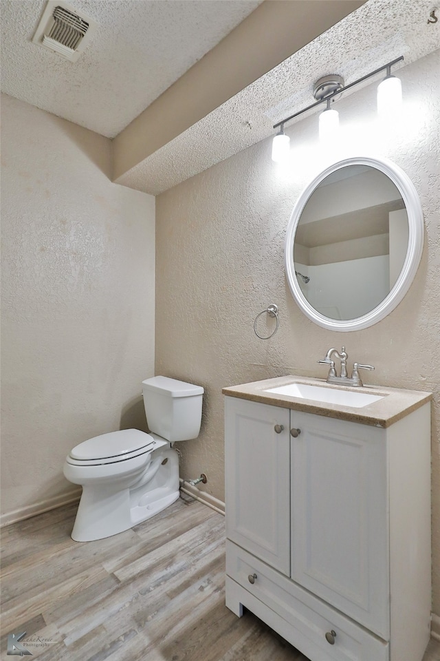 bathroom featuring vanity, a textured ceiling, wood-type flooring, and toilet