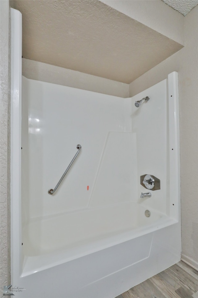 bathroom with tub / shower combination, a textured ceiling, and hardwood / wood-style flooring