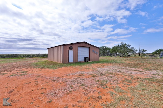 view of outbuilding featuring a rural view, a garage, and central air condition unit