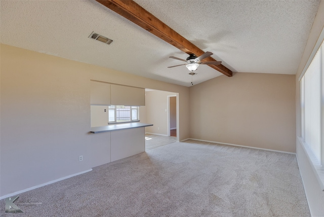 carpeted empty room with ceiling fan, a textured ceiling, and vaulted ceiling with beams