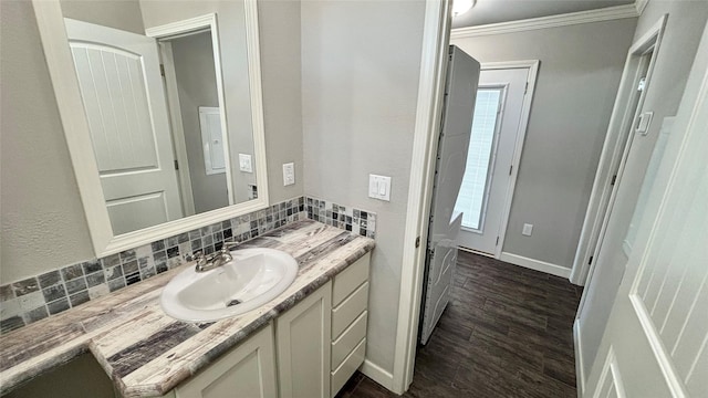 bathroom featuring hardwood / wood-style floors, vanity, ornamental molding, and backsplash