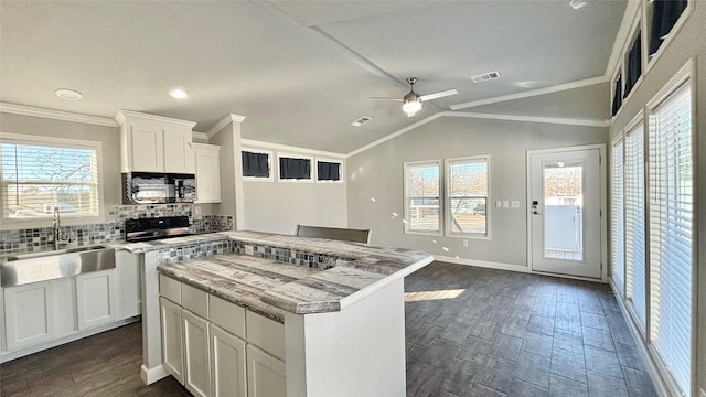 kitchen featuring lofted ceiling, sink, backsplash, plenty of natural light, and white cabinets