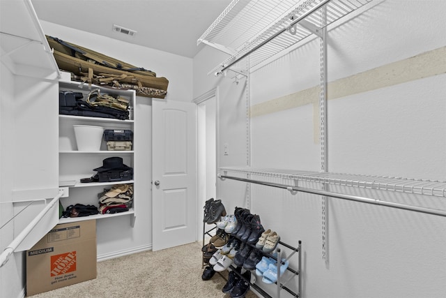 walk in closet featuring light colored carpet