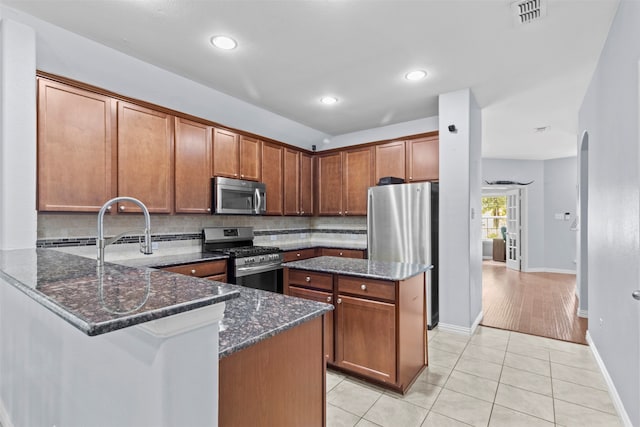 kitchen with stainless steel appliances, backsplash, and dark stone countertops