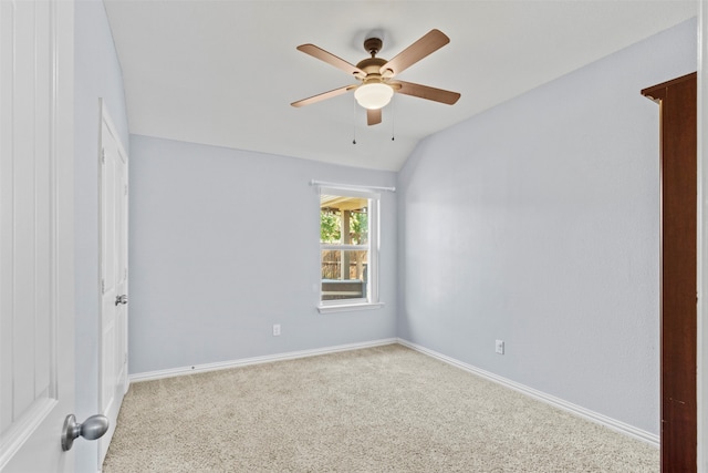 carpeted spare room featuring vaulted ceiling and ceiling fan