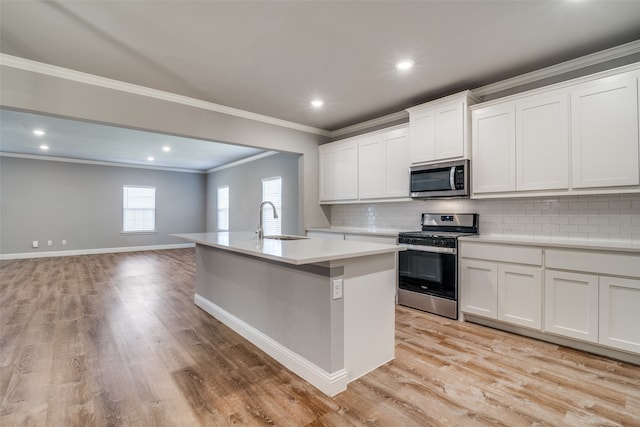 kitchen with appliances with stainless steel finishes, sink, an island with sink, and white cabinets