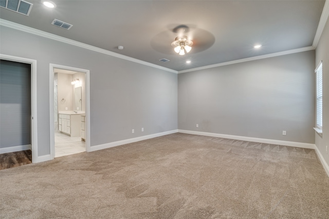 unfurnished bedroom featuring crown molding, ensuite bathroom, light colored carpet, and ceiling fan