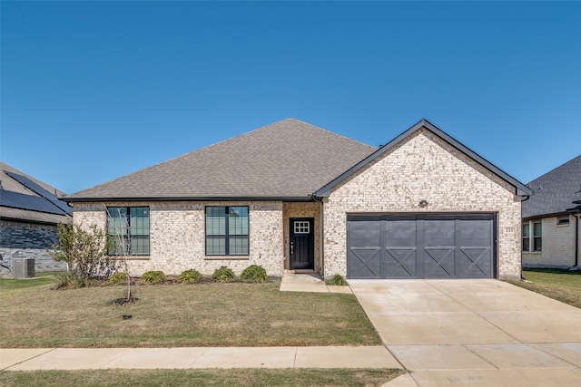 view of front of home featuring central air condition unit, a front lawn, and a garage