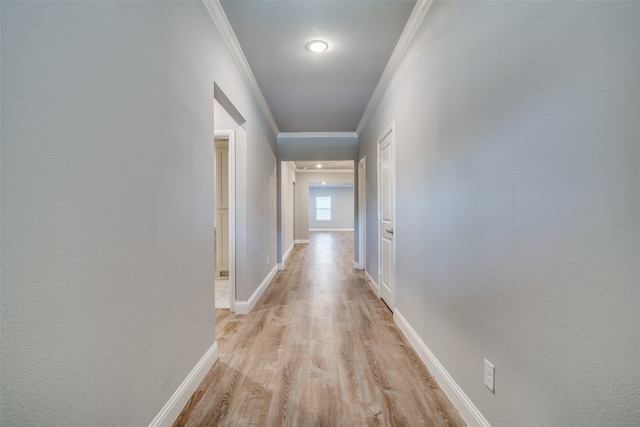 corridor with ornamental molding and light hardwood / wood-style flooring