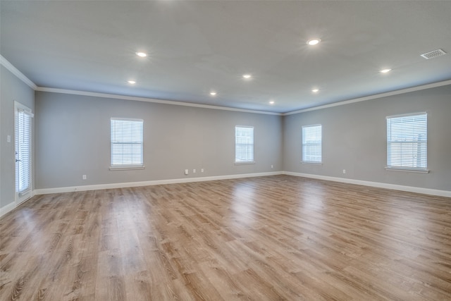 empty room featuring light hardwood / wood-style floors, crown molding, and plenty of natural light