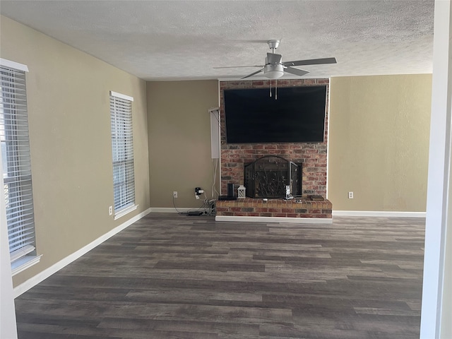 unfurnished living room with a textured ceiling, dark wood-type flooring, a fireplace, and ceiling fan