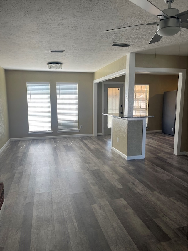 unfurnished living room with dark hardwood / wood-style floors, a textured ceiling, and ceiling fan