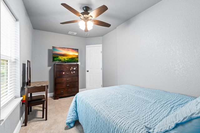 bedroom with a ceiling fan, baseboards, visible vents, and light carpet