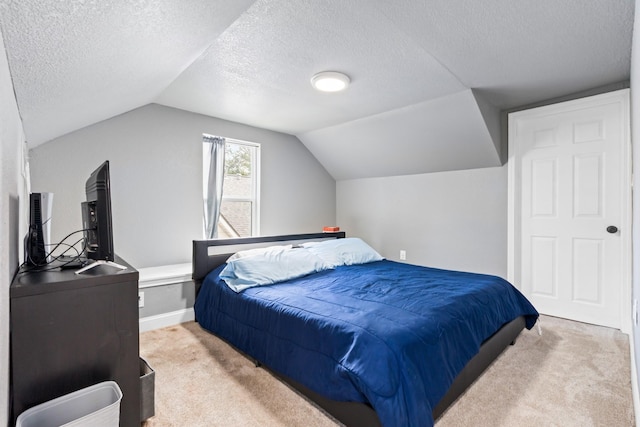 bedroom featuring carpet, vaulted ceiling, and a textured ceiling