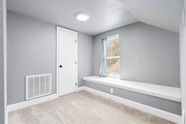 interior space with a textured ceiling, visible vents, baseboards, lofted ceiling, and a textured wall