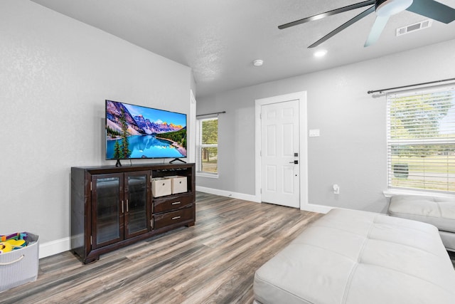 living area featuring visible vents, baseboards, ceiling fan, and wood finished floors