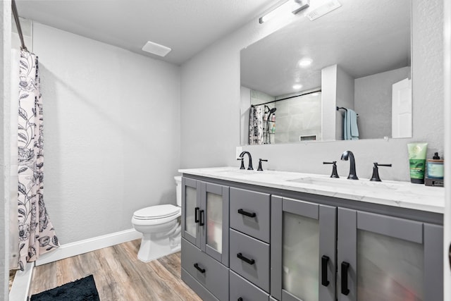 full bath with double vanity, a sink, wood finished floors, and toilet