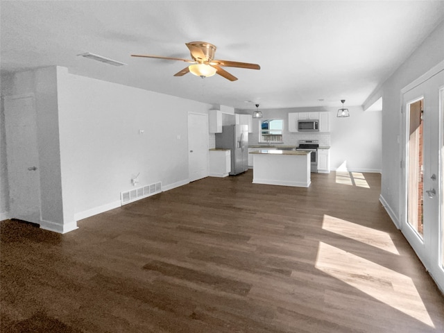 unfurnished living room featuring dark wood-type flooring and ceiling fan