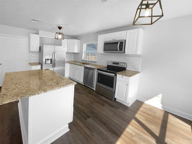 kitchen with white cabinetry, appliances with stainless steel finishes, pendant lighting, and dark hardwood / wood-style floors