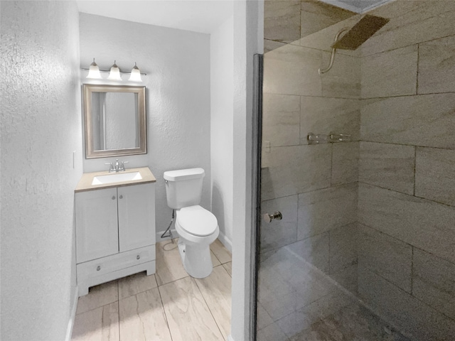 bathroom with vanity, a tile shower, and toilet