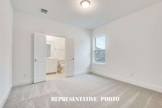 unfurnished bedroom with light colored carpet and ensuite bath