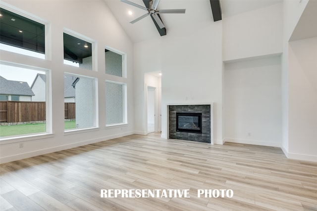 unfurnished living room featuring a tiled fireplace, high vaulted ceiling, light wood-type flooring, and ceiling fan