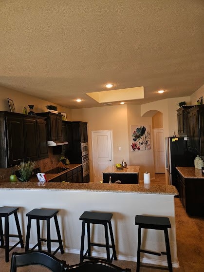 kitchen featuring a breakfast bar, a textured ceiling, and a kitchen island