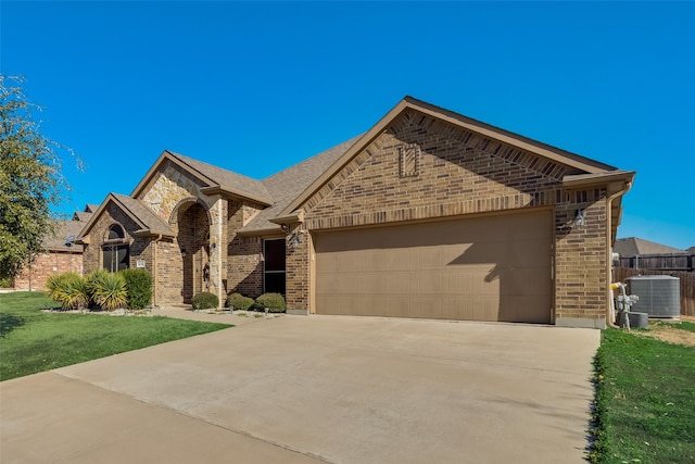 view of front of home with cooling unit, a garage, and a front lawn