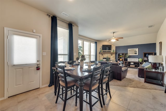 dining room featuring light colored carpet, a fireplace, and ceiling fan