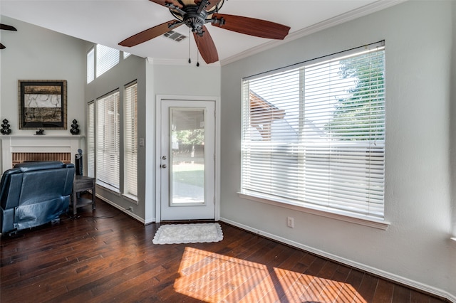 doorway to outside with crown molding, ceiling fan, a brick fireplace, and dark hardwood / wood-style flooring