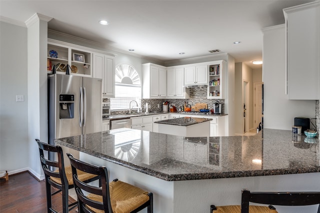 kitchen with kitchen peninsula, white cabinetry, dark stone countertops, and dark hardwood / wood-style flooring