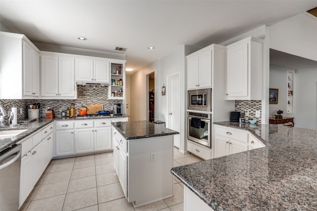 kitchen featuring white cabinetry, stainless steel appliances, dark stone counters, and a kitchen island