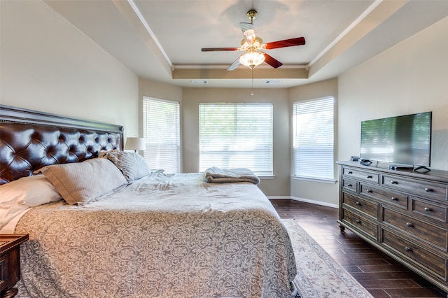 bedroom with dark hardwood / wood-style floors, a tray ceiling, and ceiling fan