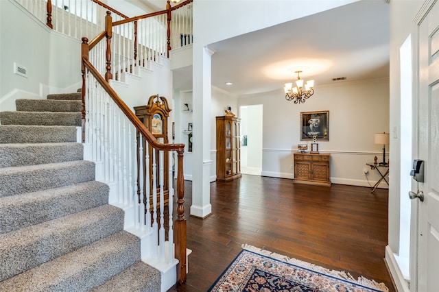 entrance foyer featuring a towering ceiling, crown molding, dark hardwood / wood-style floors, and a chandelier