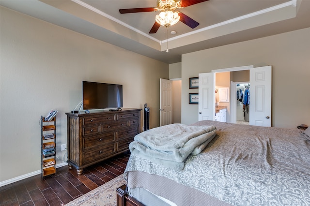 bedroom with ornamental molding, dark wood-type flooring, a raised ceiling, and ceiling fan