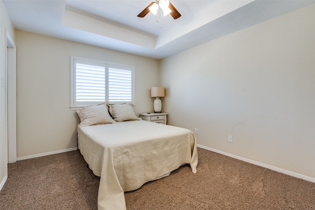 bedroom with carpet, a raised ceiling, and ceiling fan