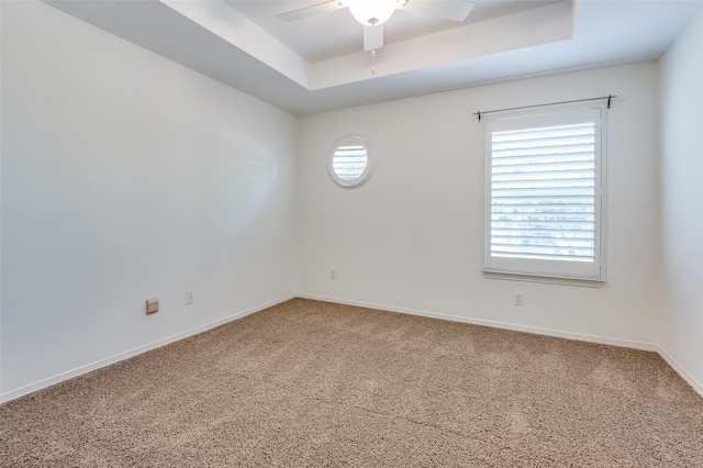 carpeted spare room featuring ceiling fan and a raised ceiling