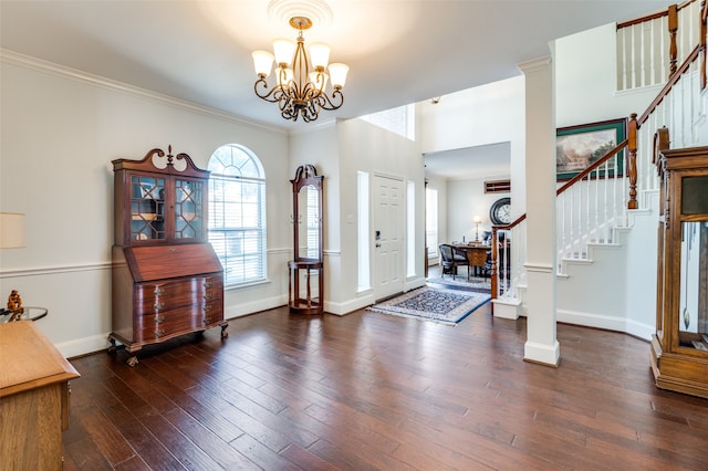 entryway featuring ornamental molding, an inviting chandelier, dark hardwood / wood-style floors, and ornate columns