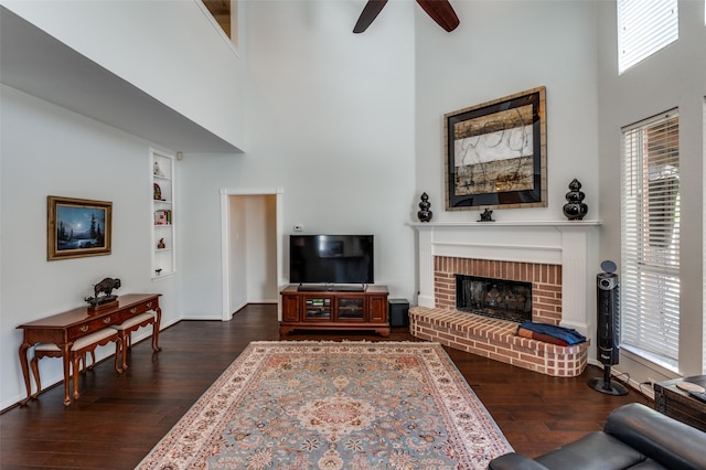 living room with built in shelves, a high ceiling, a fireplace, and dark hardwood / wood-style floors