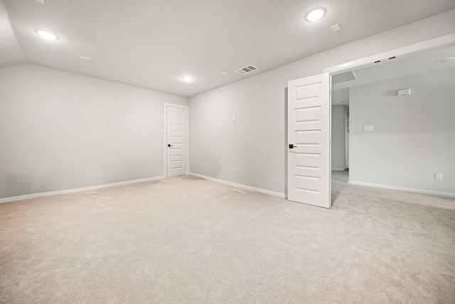 unfurnished room featuring light carpet and vaulted ceiling