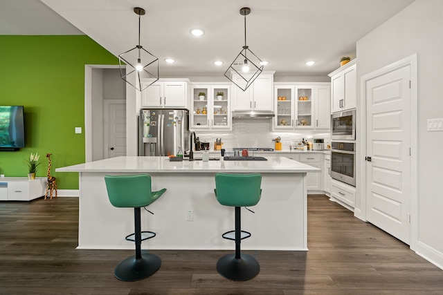 kitchen featuring white cabinets, a kitchen island with sink, stainless steel appliances, and a breakfast bar area