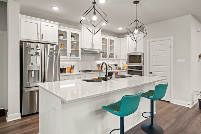 kitchen with appliances with stainless steel finishes, white cabinetry, dark wood-type flooring, and an island with sink