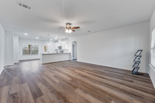 unfurnished living room with dark hardwood / wood-style flooring and ceiling fan