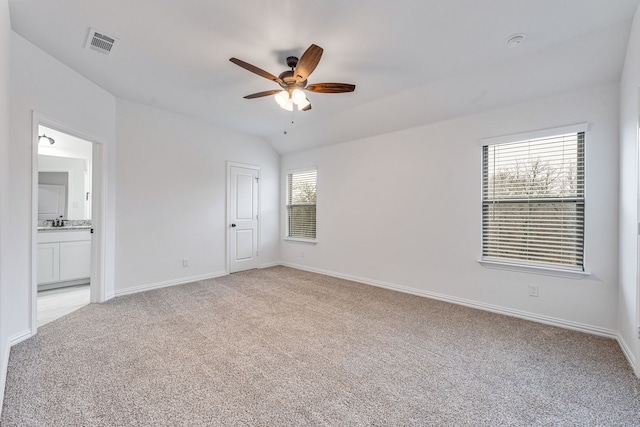 unfurnished bedroom with lofted ceiling, light colored carpet, ceiling fan, and ensuite bathroom