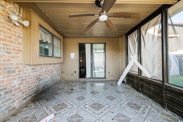 unfurnished sunroom with ceiling fan, wooden ceiling, and a wealth of natural light