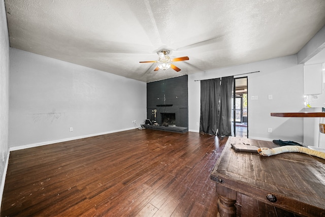 living room featuring hardwood / wood-style floors, a fireplace, a textured ceiling, and ceiling fan