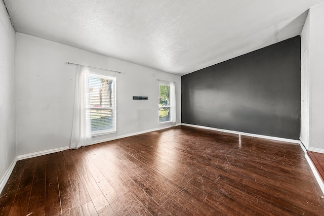 empty room featuring dark wood-type flooring and a textured ceiling