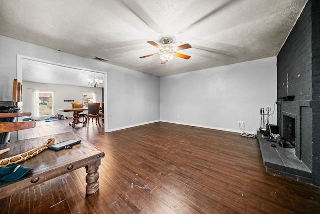 living room with dark wood-type flooring, ceiling fan, a textured ceiling, and a brick fireplace