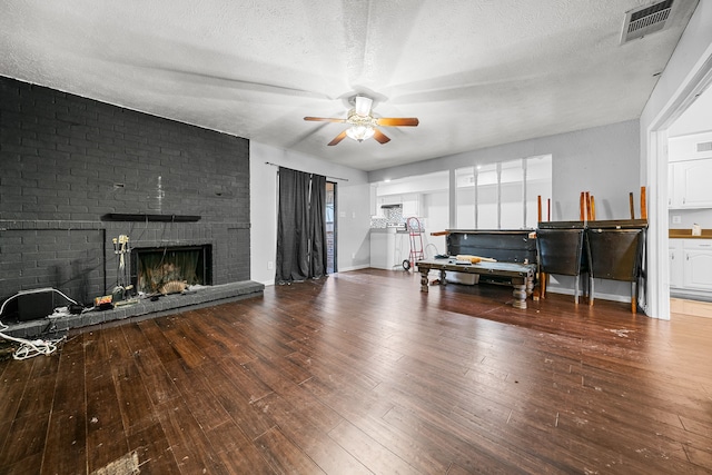 living room with a textured ceiling, a fireplace, hardwood / wood-style flooring, and ceiling fan