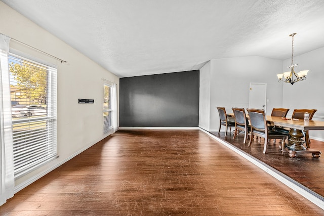 interior space featuring dark wood-type flooring, vaulted ceiling, a textured ceiling, and a chandelier